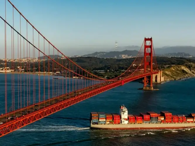 A wide view of the Golden Gate Bridge with a ship passing underneath
